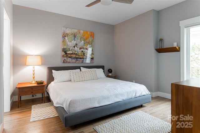 bedroom with light wood-type flooring, ceiling fan, and baseboards
