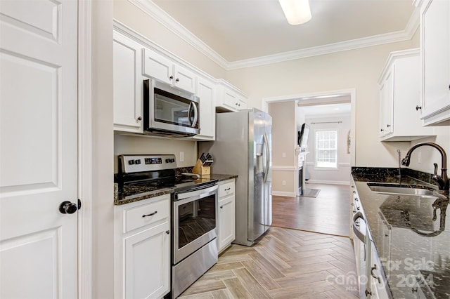 kitchen with light parquet floors, sink, dark stone countertops, white cabinetry, and stainless steel appliances