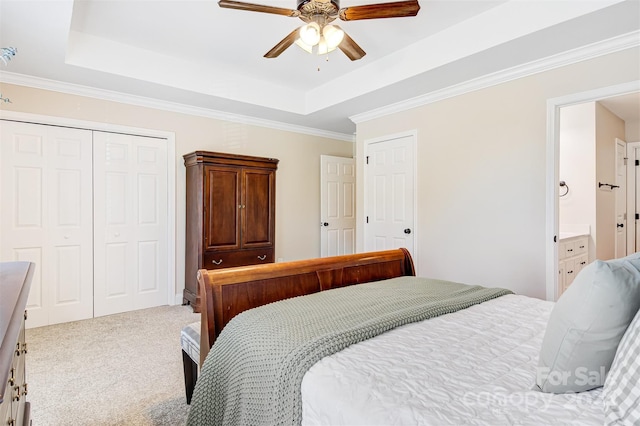 carpeted bedroom featuring ceiling fan, crown molding, ensuite bathroom, and a tray ceiling