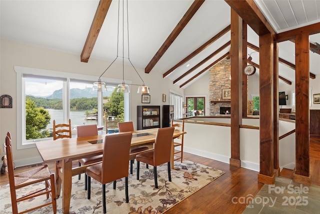 dining space featuring a water and mountain view, a wealth of natural light, and beam ceiling