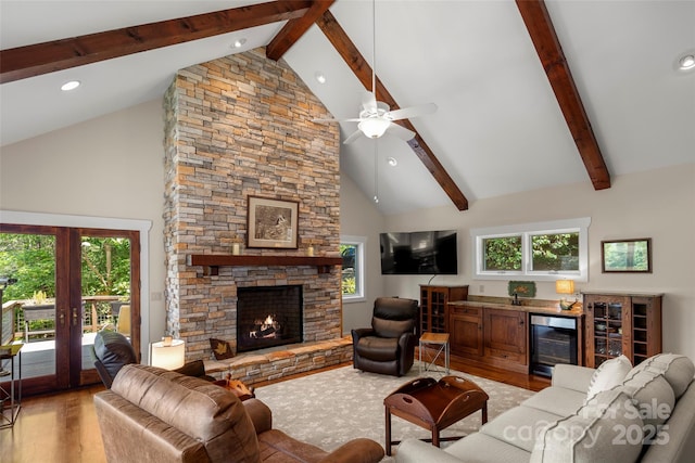 living room with light hardwood / wood-style flooring, beverage cooler, high vaulted ceiling, and a fireplace