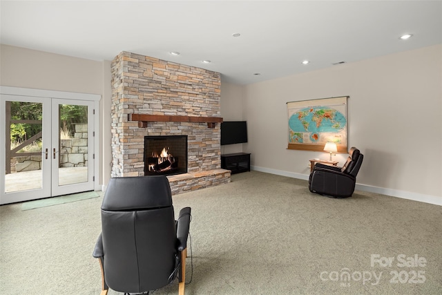 carpeted living room featuring french doors and a stone fireplace