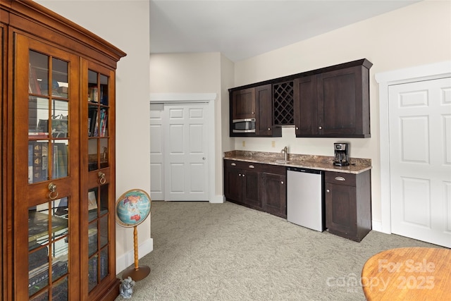 kitchen with sink, dark brown cabinets, stainless steel dishwasher, and light colored carpet