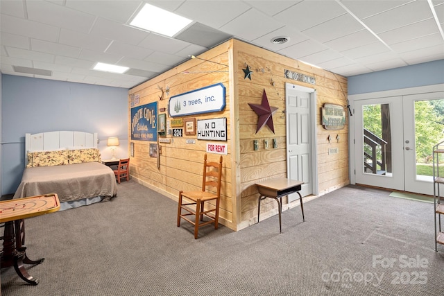 bedroom featuring french doors, access to outside, carpet, and wood walls