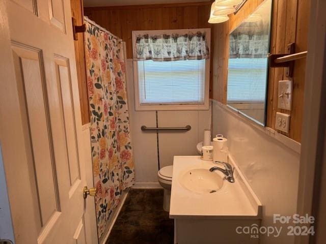 bathroom featuring wooden walls, vanity, toilet, and tile floors