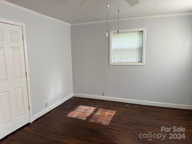 empty room with ornamental molding, dark wood-type flooring, and ceiling fan