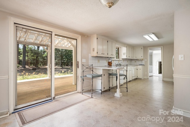 kitchen with sink, a textured ceiling, white cabinetry, and backsplash