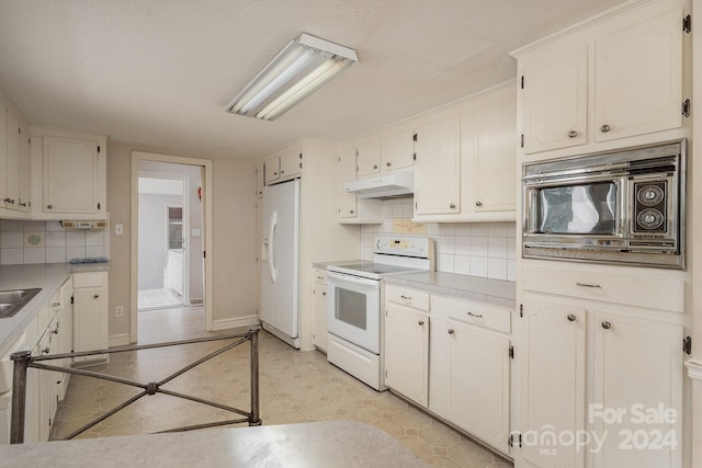 kitchen with white appliances, decorative backsplash, and white cabinets