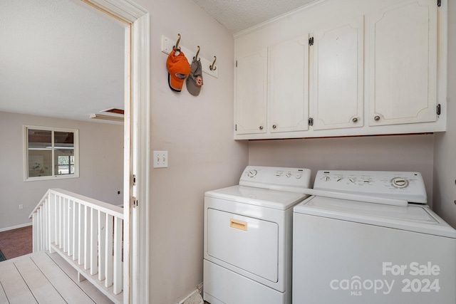 laundry room with washing machine and clothes dryer, a textured ceiling, and cabinets