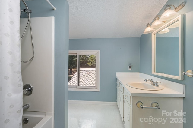 bathroom featuring a textured ceiling, shower / bath combination with curtain, and vanity