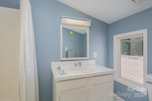 bathroom featuring toilet, a textured ceiling, lofted ceiling, and vanity