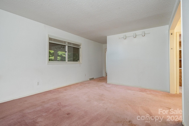 spare room with a textured ceiling and carpet flooring