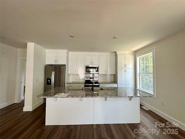 kitchen with a sink, baseboards, white cabinetry, and stainless steel appliances