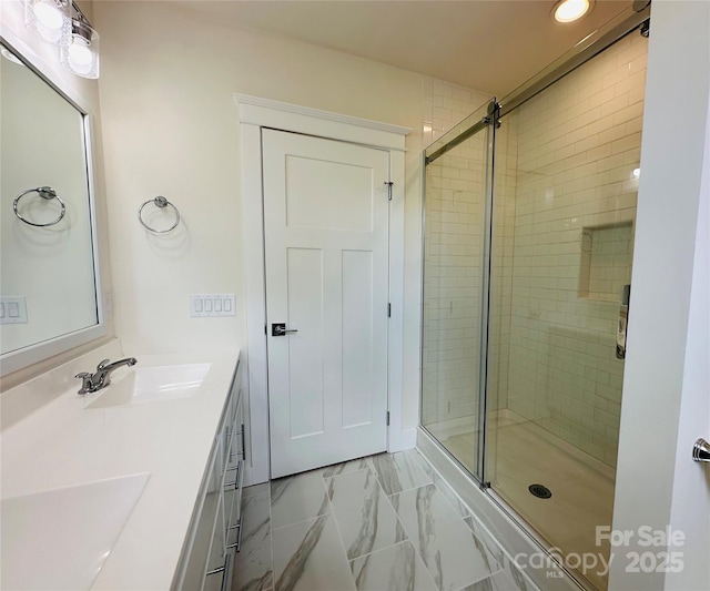bathroom with a stall shower, marble finish floor, and a sink