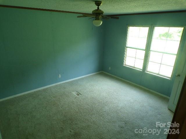 empty room with ceiling fan, carpet floors, and a textured ceiling