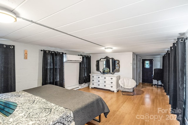 bedroom featuring light wood-type flooring and an AC wall unit