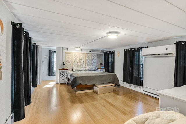 bedroom featuring light hardwood / wood-style floors, a wall unit AC, and a baseboard radiator