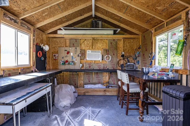 interior space featuring a wall mounted air conditioner, a workshop area, and lofted ceiling