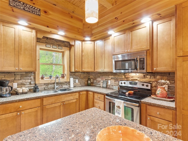 kitchen featuring appliances with stainless steel finishes, sink, tasteful backsplash, and light stone countertops