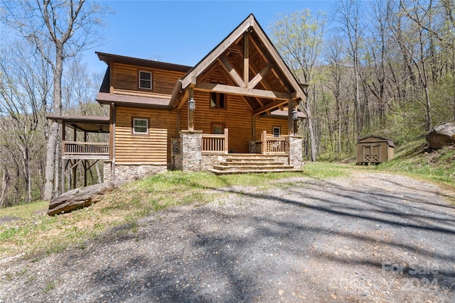 log home featuring covered porch and a storage unit