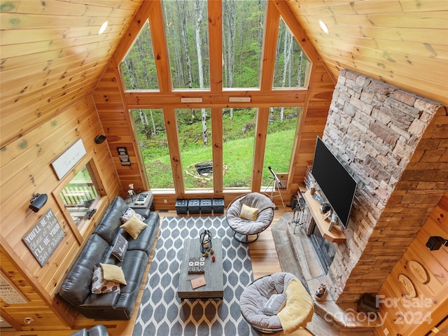 living room with a healthy amount of sunlight, high vaulted ceiling, and wood walls