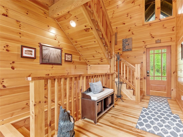 entryway with wooden ceiling, vaulted ceiling, wood walls, and light hardwood / wood-style flooring