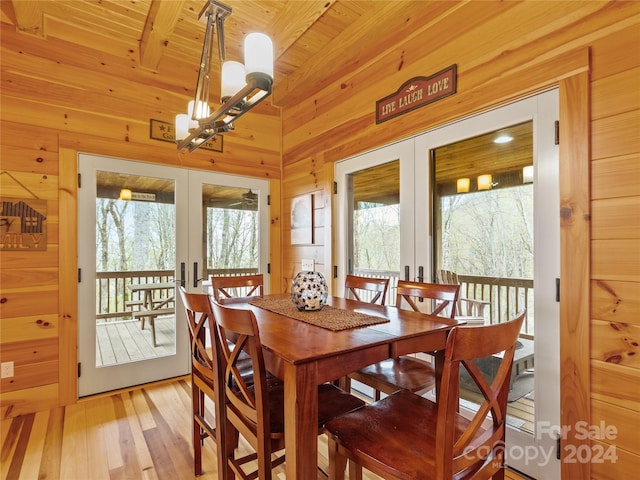 dining room featuring a wealth of natural light, wooden ceiling, wooden walls, and light hardwood / wood-style flooring