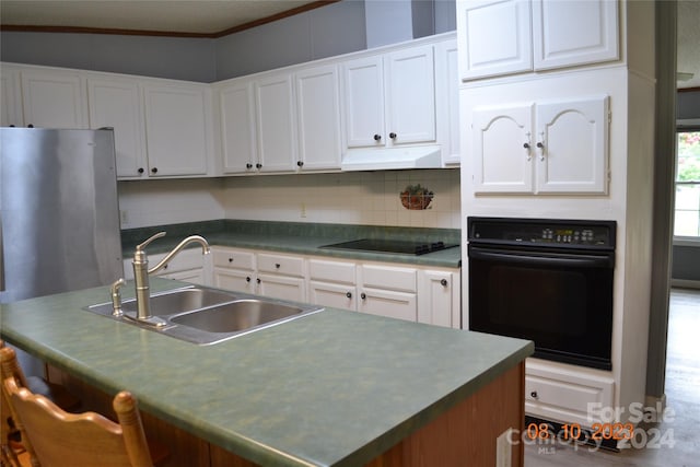 kitchen featuring tasteful backsplash, black appliances, range hood, sink, and a kitchen island with sink