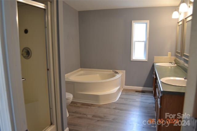 full bathroom with independent shower and bath, hardwood / wood-style floors, vanity with extensive cabinet space, toilet, and dual sinks