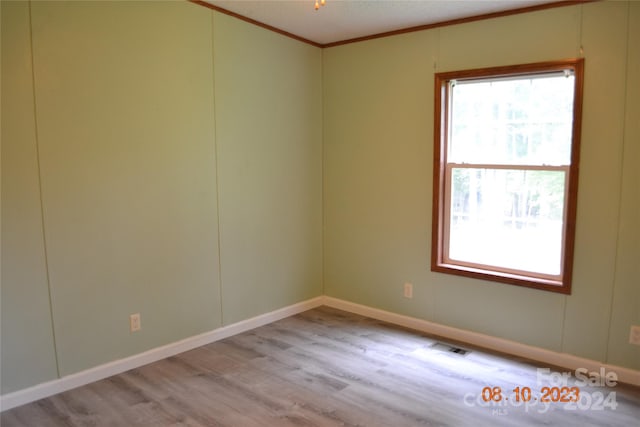 unfurnished room with plenty of natural light, hardwood / wood-style flooring, and crown molding