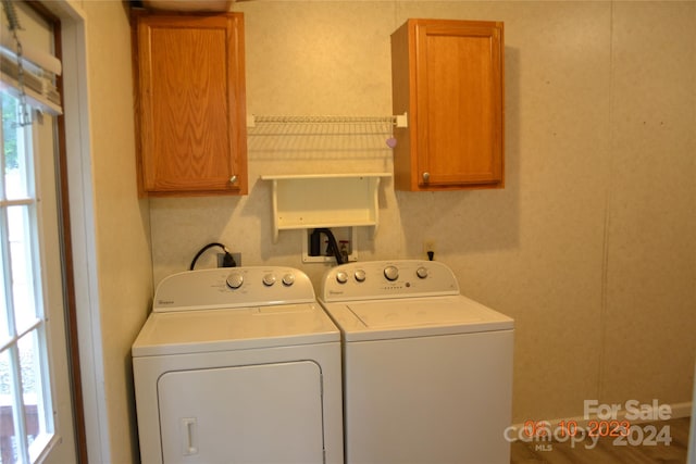 laundry area with hookup for a washing machine, washer and dryer, and cabinets