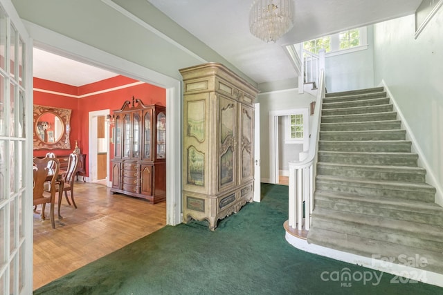 entryway featuring an inviting chandelier, a wealth of natural light, and carpet flooring