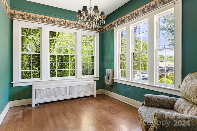 living area featuring a notable chandelier, a wall mounted air conditioner, hardwood / wood-style floors, and radiator heating unit