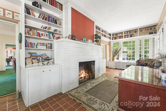 living room featuring a brick fireplace, dark tile patterned flooring, a textured ceiling, built in shelves, and radiator heating unit