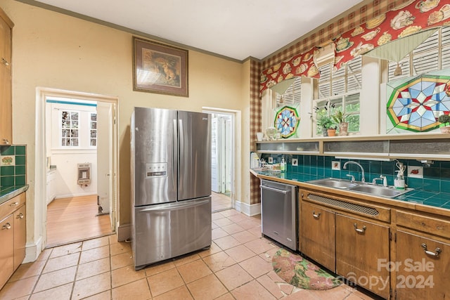 kitchen featuring appliances with stainless steel finishes, tile counters, backsplash, light tile patterned flooring, and sink