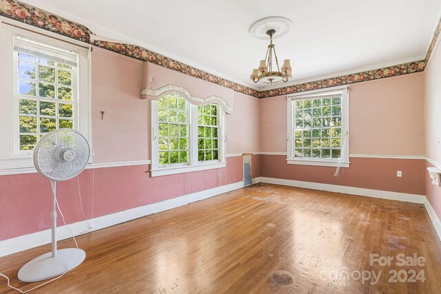 spare room with a notable chandelier, crown molding, and hardwood / wood-style flooring