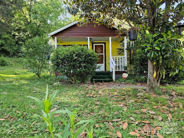 view of outbuilding with covered porch and a lawn