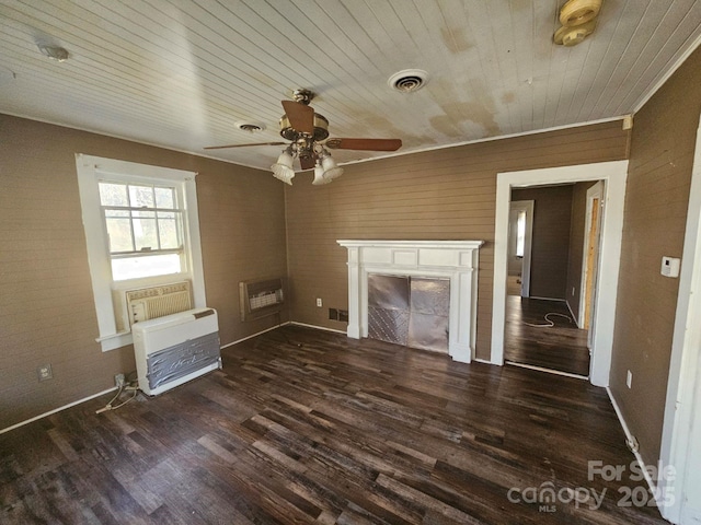 unfurnished living room featuring ceiling fan, heating unit, and dark hardwood / wood-style floors