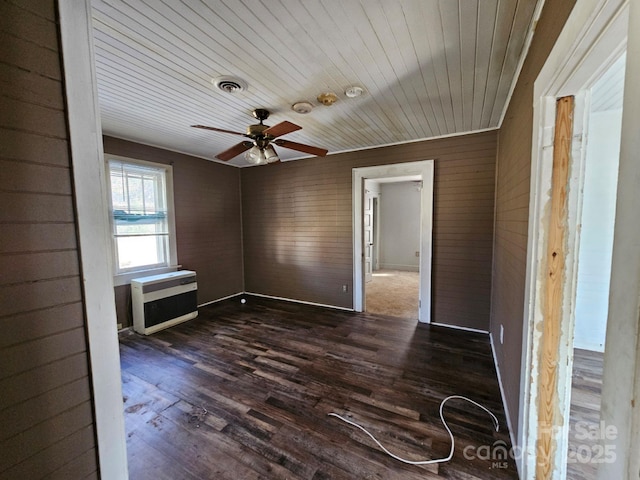 unfurnished room featuring wooden ceiling, wood walls, heating unit, ceiling fan, and dark hardwood / wood-style floors