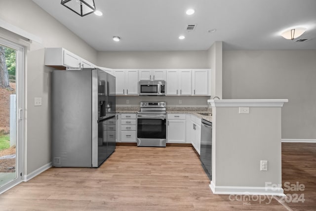 kitchen featuring white cabinetry, sink, kitchen peninsula, appliances with stainless steel finishes, and light wood-type flooring