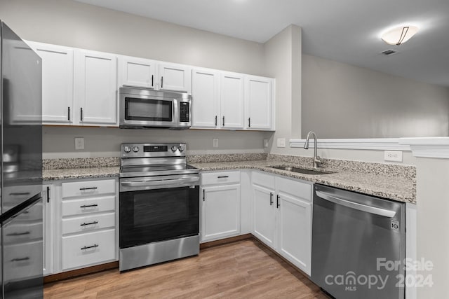 kitchen featuring white cabinetry, sink, stainless steel appliances, and light hardwood / wood-style flooring