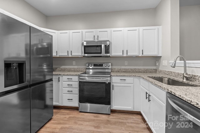 kitchen with white cabinetry, sink, stainless steel appliances, light stone counters, and light wood-type flooring