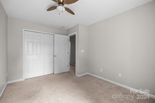 unfurnished bedroom featuring light carpet, a closet, and ceiling fan