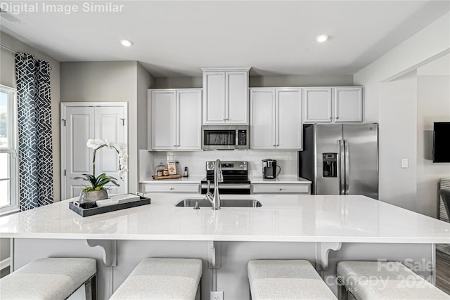 kitchen featuring white cabinetry, a breakfast bar, a large island with sink, and appliances with stainless steel finishes