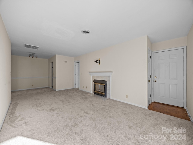 unfurnished living room featuring light carpet and a tile fireplace