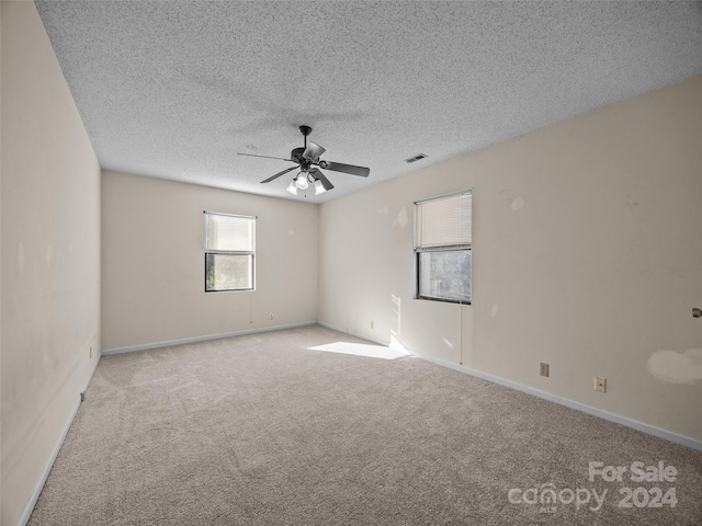 carpeted spare room featuring a textured ceiling and ceiling fan