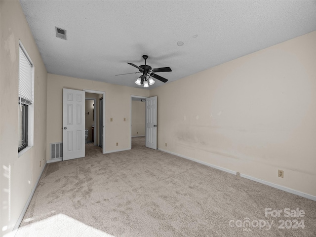 unfurnished bedroom featuring a textured ceiling, light colored carpet, and ceiling fan