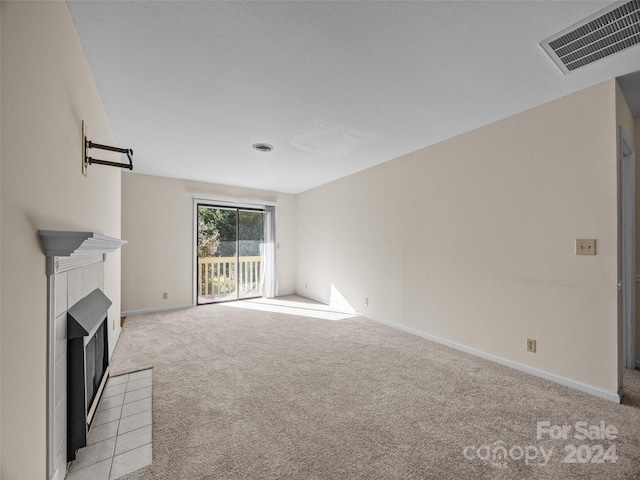 unfurnished living room with a tile fireplace and light colored carpet