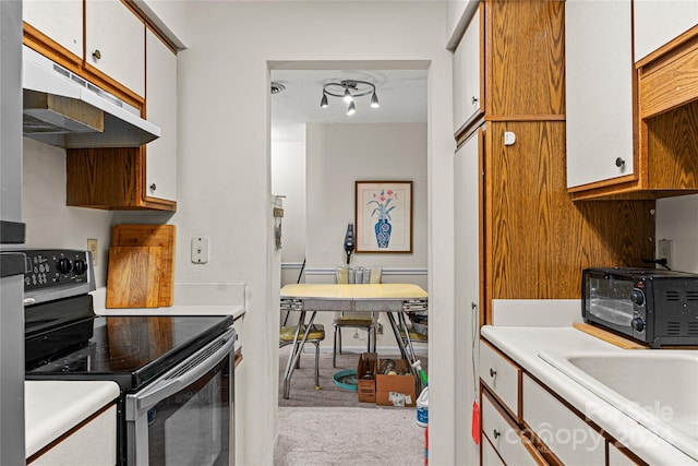 kitchen featuring stainless steel electric stove, light colored carpet, and white cabinets