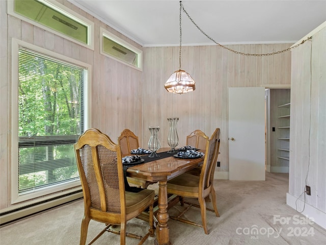 dining room with a baseboard heating unit, carpet flooring, wooden walls, and an inviting chandelier